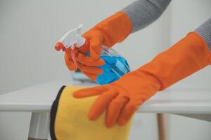 Woman cleaning table using rag and diffuser at home. photo