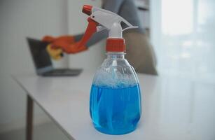 Woman cleaning table using rag and diffuser at home. photo
