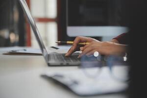 Cropped image of professional businesswoman working at her office via laptop, young female manager using portable computer device while sitting at modern loft, flare light, work process concept photo