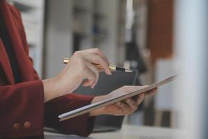 Cropped image of professional businesswoman working at her office via laptop, young female manager using portable computer device while sitting at modern loft, flare light, work process concept photo