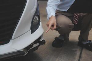 Side view of writing on clipboard while insurance agent examining car after accident photo