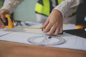 engineer people meeting working and pointing at a blueprint in office for discussing. Engineering tools and construction concept photo