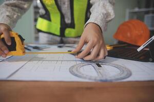 engineer people meeting working and pointing at a blueprint in office for discussing. Engineering tools and construction concept photo