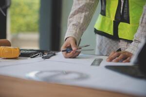 engineer people meeting working and pointing at a blueprint in office for discussing. Engineering tools and construction concept photo