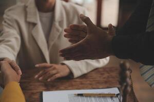 Lawyer shaking hands with a client making about documents, contracts, agreements, cooperation agreements with a female client at the lawyer's desk and a hammer at the table. photo