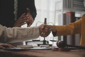 Lawyer shaking hands with a client making about documents, contracts, agreements, cooperation agreements with a female client at the lawyer's desk and a hammer at the table. photo