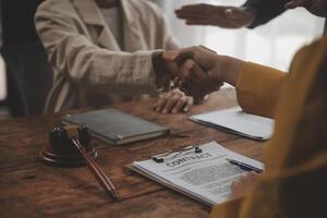 Lawyer shaking hands with a client making about documents, contracts, agreements, cooperation agreements with a female client at the lawyer's desk and a hammer at the table. photo