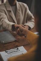 Lawyer shaking hands with a client making about documents, contracts, agreements, cooperation agreements with a female client at the lawyer's desk and a hammer at the table. photo