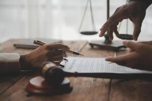 Business and lawyers discussing contract papers with brass scale on desk in office. Law, legal services, advice, justice and law concept picture with film grain effect photo