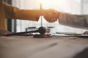 Lawyer shaking hands with a client making about documents, contracts, agreements, cooperation agreements with a female client at the lawyer's desk and a hammer at the table. photo