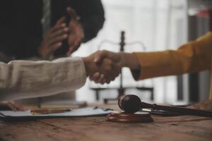 Lawyer shaking hands with a client making about documents, contracts, agreements, cooperation agreements with a female client at the lawyer's desk and a hammer at the table. photo