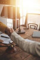 Lawyer shaking hands with a client making about documents, contracts, agreements, cooperation agreements with a female client at the lawyer's desk and a hammer at the table. photo