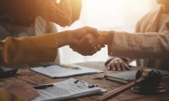 Lawyer shaking hands with a client making about documents, contracts, agreements, cooperation agreements with a female client at the lawyer's desk and a hammer at the table. photo