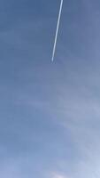 Jet aircraft plane with a bright white contrail as it flies across a blue sky. A view from below of an airplane flying in the blue sky. Good background for graphics or travel . video