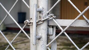 Close up of padlock on white metal gate in front of house. Security concept. photo