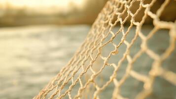 Rope Netting with Sunlit Ocean Background, Nautical Theme, Fishing Net Close-Up, Warm Tones, Outdoors, Tranquil Coastal Scene at Sunset, Blurred Background, Soft Focus, Marine Texture photo