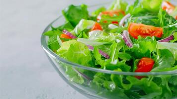 Fresh Green Salad with Lettuce, Cherry Tomatoes, and Red Onion in Glass Bowl on Light Background photo