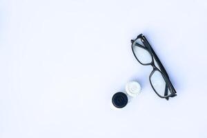 Top view of eyeglasses and contact lenses in container on white background. photo