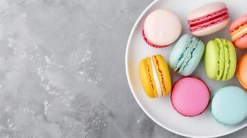 Overhead View of Colorful Macarons on White Plate Against Gray Textured Background Dessert, Confectionery Themes, and French Bakery Concepts in Food Photography, Still Life and Minimalist Design photo