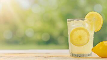 Refreshing Glass of Lemonade with Lemon Slices on Wooden Table with Green Bokeh Background for Summer Concept and Design photo