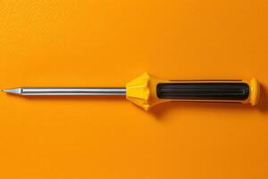 Yellow screwdriver resting on an orange surface in a well-lit workspace photo