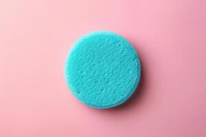 Bright blue sponge on a soft pink background photo
