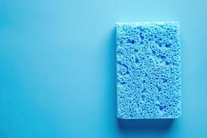 Blue sponge on a solid light blue background for cleaning and household use photo