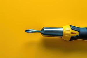 Close-up of a yellow and black screwdriver tool against a bright yellow background photo