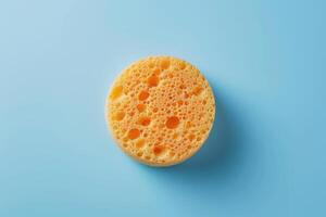 Bright orange sponge on a light blue background photo