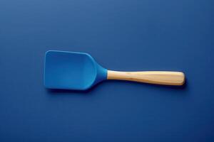 Blue silicone spatula with wooden handle on a dark blue background photo