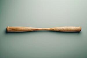A wooden baseball bat lying flat on a green background in a minimalist setting photo
