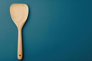 Wooden cooking spatula on dark blue countertop in a kitchen setting photo