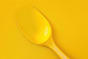 Bright yellow kitchen spatula resting on a vibrant yellow surface photo