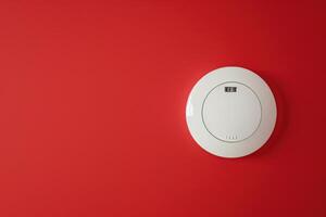 Circular smoke detector mounted on a vibrant red wall in a modern interior space photo