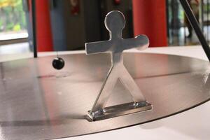 A metal human figure and a pendulum ball near it. The concept of human endurance and resilience in the face of adversity and difficulties. photo