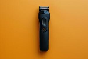 A sleek black electric shaver placed against a vibrant orange background photo
