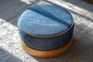 Round blue fabric cushion on wooden base in natural light photo
