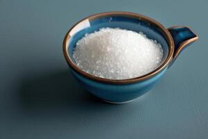 Bowl of coarse salt on a blue surface with a simple and elegant design photo