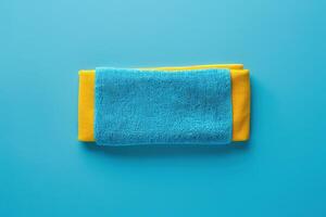 Stack of blue and yellow towels on a vibrant turquoise background photo