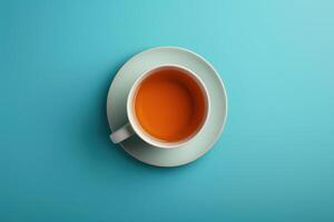 Cup of orange tea on a mint green saucer against a light blue background photo