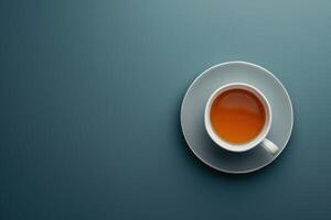 A steaming cup of tea on a simple saucer against a blue background photo