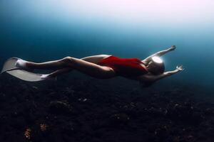 Sexy woman freedives. Young sporty female freediver swims underwater in deep ocean photo