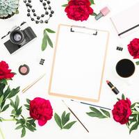 Workspace with diary, retro photo camera, peonies flowers, clipboard and accessories on white background. Flat lay, top view. Copy space