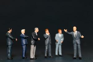 Miniature people Businessman standing on black background , Concept of Business leader and teamwork photo