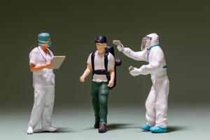A miniature scene depicts a traveler being screened by healthcare workers photo