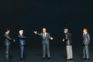 Miniature people Businessman standing on black background , Concept of Business leader and teamwork photo