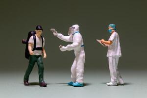 A miniature scene depicts a traveler being screened by healthcare workers photo