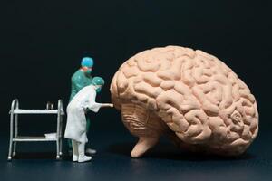 Miniature people of surgeons examining a large brain model photo