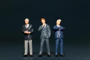 Miniature people Businessman standing on black background , Concept of Business leader and teamwork photo