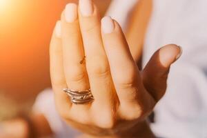 Ant walking by woman hand with a ring with feathers on her finger photo